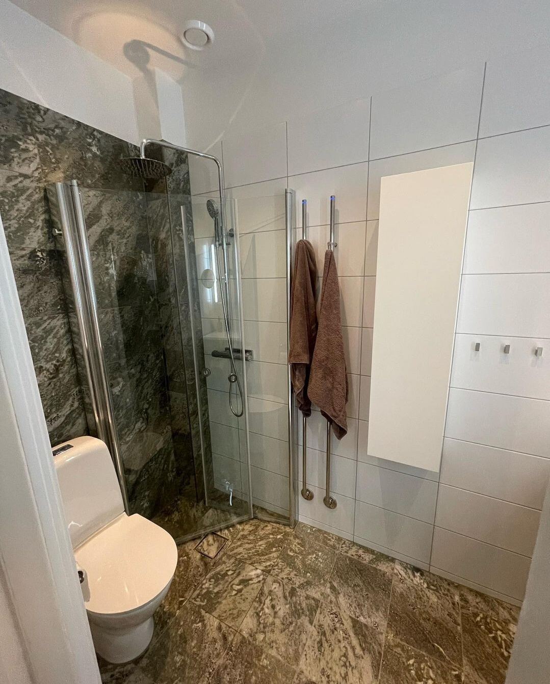 Renoverat badrum: Vitt kvadratiskt kakel, grön marmordusch, brunt marmorgolv