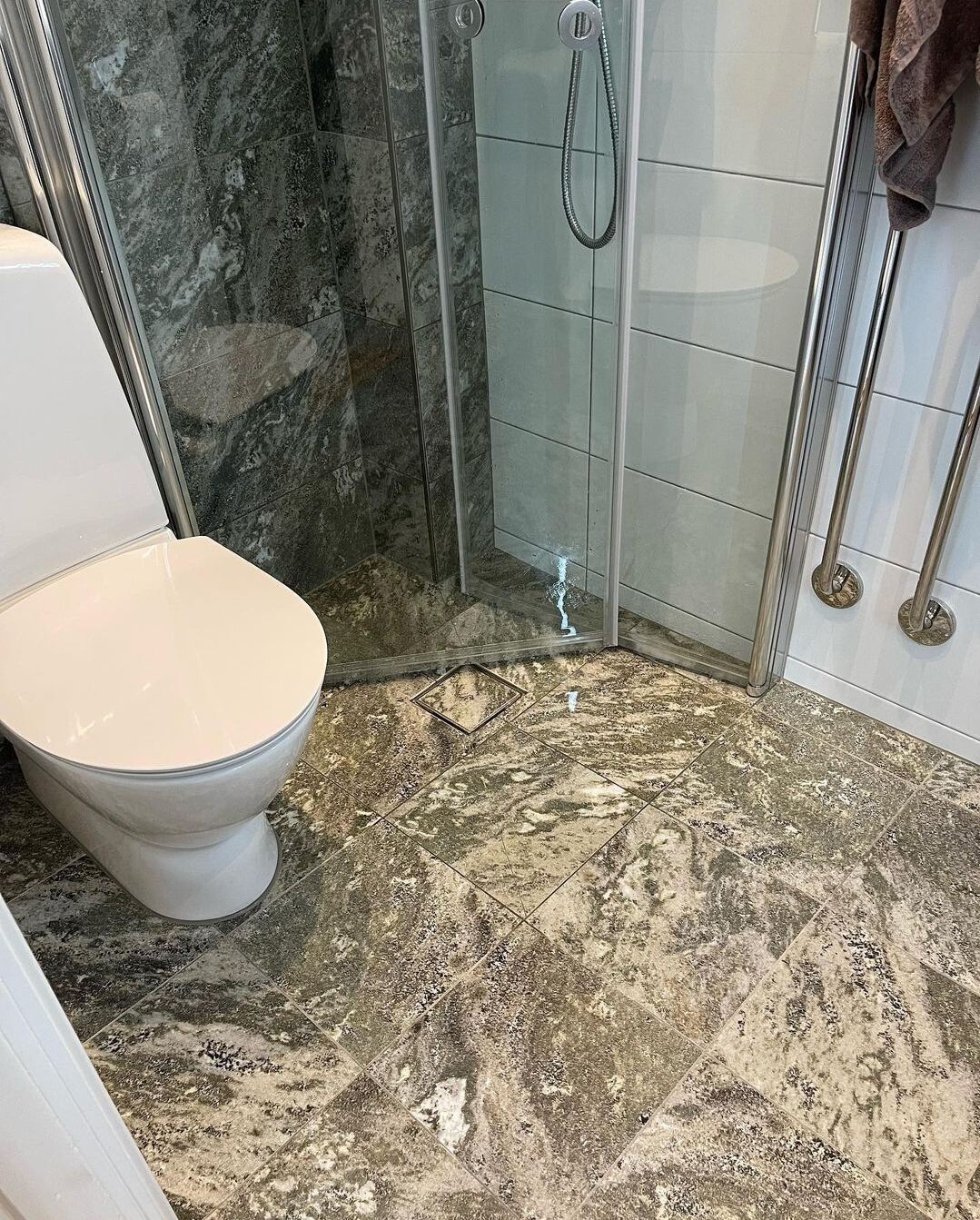 Renoverat badrum: Vitt kvadratiskt kakel, grön marmordusch, brunt marmorgolv