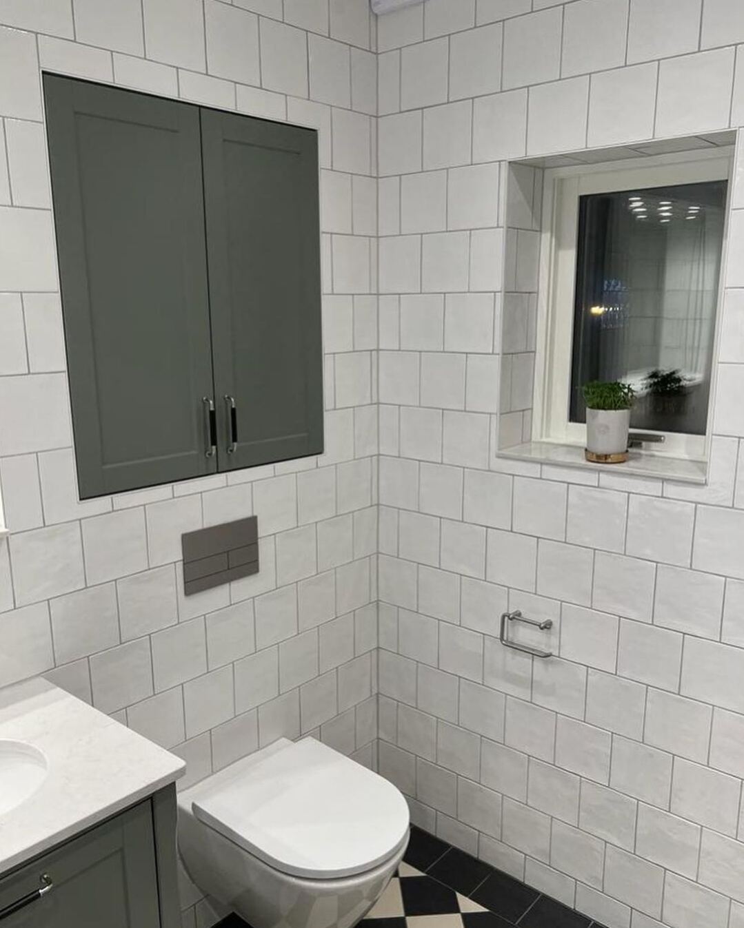 Renoverat badrum: Vitt kakel + schackrutigt golv, fristående badkar, grön kommod