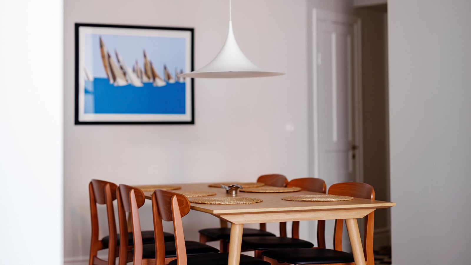 Matbord i ek med konst på väggen i vitt kök